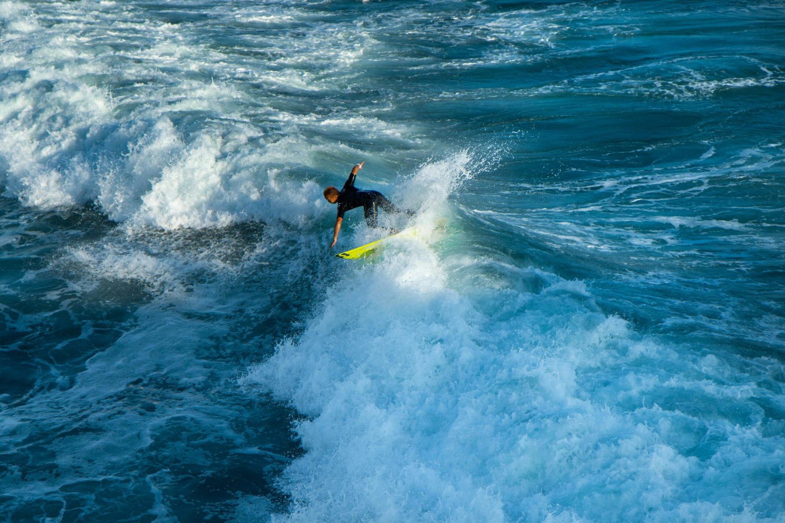 Surfer skillfully rides the powerful waves at Huntington Beach, California, under a clear sky.
