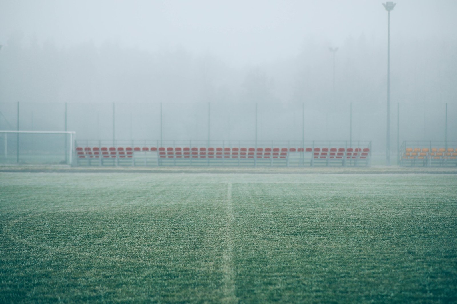 Foggy soccer field with empty bleachers, creating a serene and mysterious atmosphere.